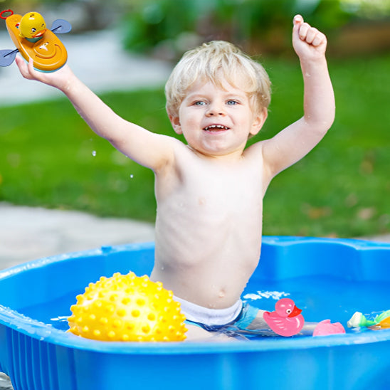 Enfant éclabousse joyeusement la piscine avec son canard en kayak.