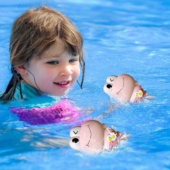 Une fille nage dans la piscine à côté de ses jouets de bain