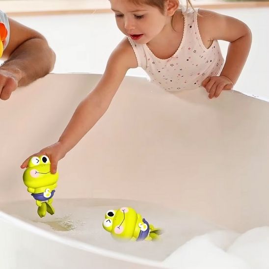 Une fille met son jouet de bain pour bebe dans la baignoire et son père admire son développement