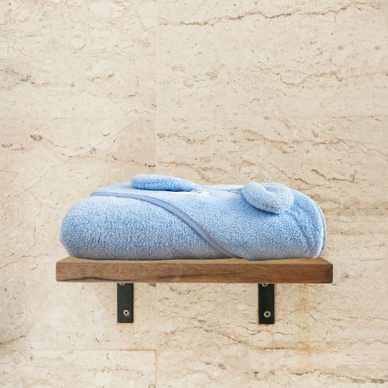 La cape de bain bébé bien pliée et ranger sur l'étagère de bain