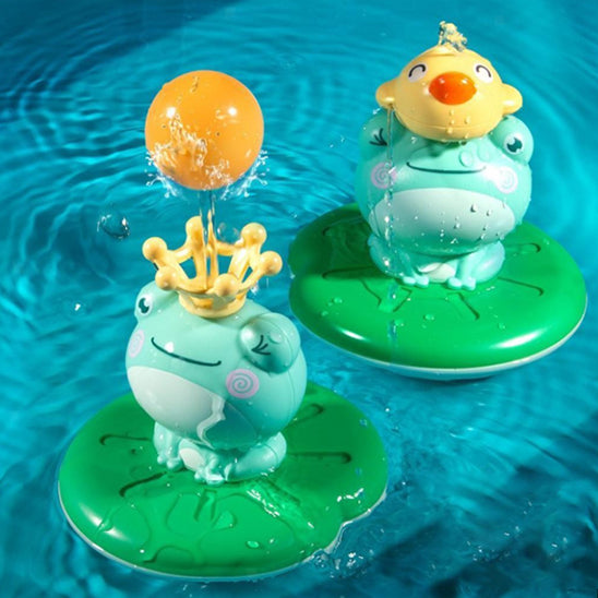 Deux jouets de bain MagikGrenouille™ flottant dans la piscine, l’un projetant de l’eau avec sa couronne, l’autre avec une tête rigolote.