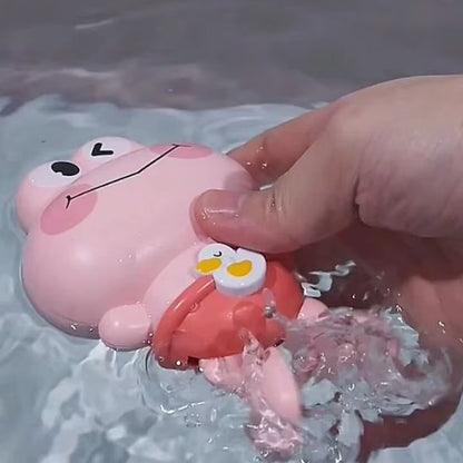 Une main lance le jouet de bain pour bebe rose dans l'eau