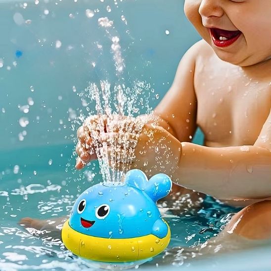 Bébé content en jouant avec les jets d'eau de son jouet de bain baleine