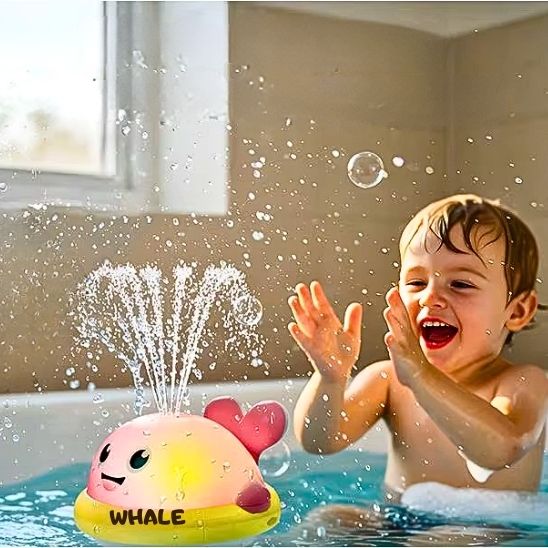 Enfant très joyeux dans son bain avec son jouet de bain baleine lumineux rose