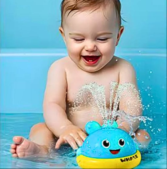 Bébé très content dans sa baignoire et occupé avec son jouet de bain baleine bleu qui fait des jets d'eau