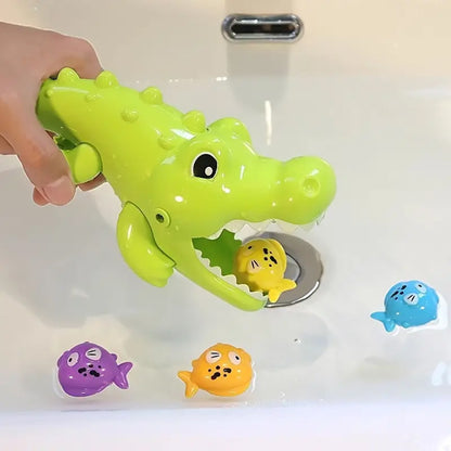 Une main tient le Mini Alligator Gourmand qui avale un poisson, tandis que les autres poissons flottent dans le lavabo