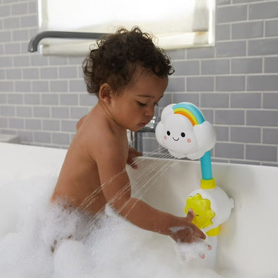 Bébé dans la baignoire appuie sur la douchette du jouet nuage fixé par ventouse, faisant jaillir de l’eau en jets ludiques.