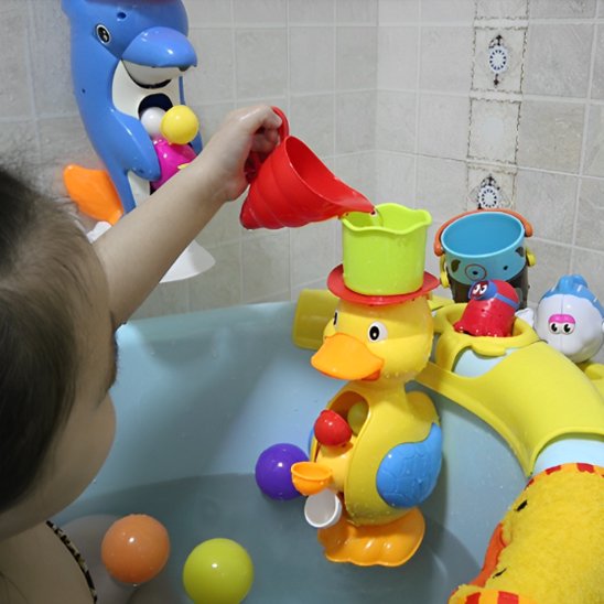 Bébé dans sa baignoire versant de l'eau dans le chapeau de son jouet de bain canard, activant la roue tournante pour un jeu aquatique interactif.