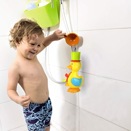 Enfant versant de l'eau dans le chapeau de son jouet de bain canard, activant la roue tournante pour un jeu aquatique interactif.