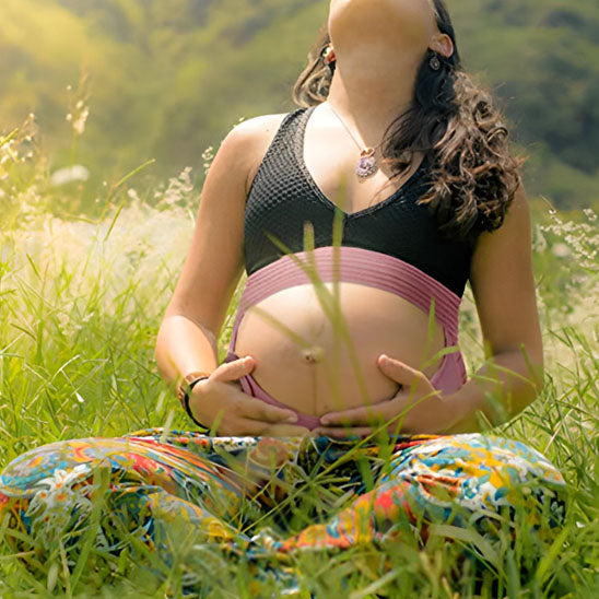 Future maman porte sa ceinture de grossesse assise en plein nature zen