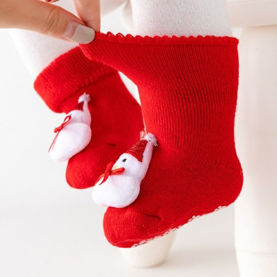 Maman montre l'élasticité de chaussette Noël bebe dans les pieds de sa petite