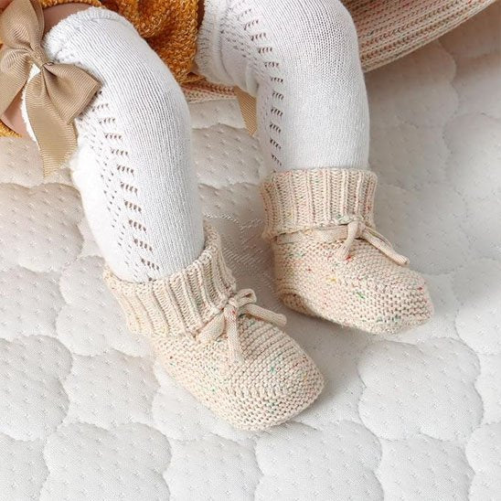 Chausson bébé en tricot coloris pastel rose et vert sauge, style doux et naturel.