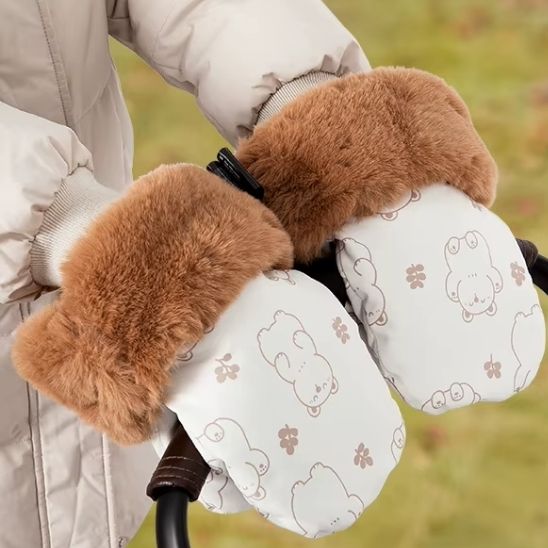Mains portant des gants de poussette au meme style que la chanceliere bebe, pendant qu’elles poussent la poussette