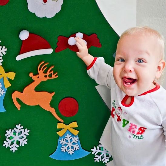 Bébé tout content est fier d'accrocher son ornement sur son sapin de Noël