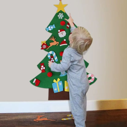 Bebe tend sa main pour accrocher l'ornement sur son sapin de Noël en feutre