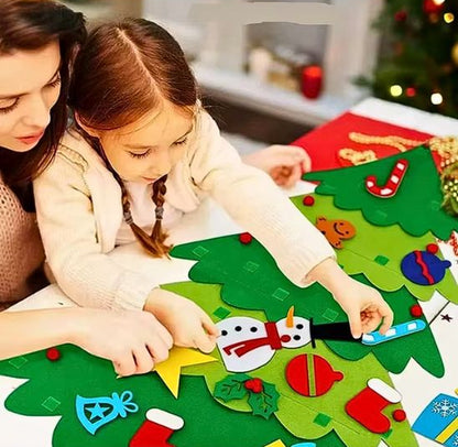 Fillette concentrée pour accroches les ornements sur son sapin de noël en feutre avec la participation de sa maman
