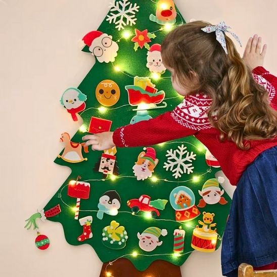 Une fillette concentrée par la décoration de son sapin d'éveil Noël